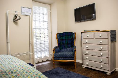 a bedroom with a dresser and a chair and a television at The Old School House in Haltwhistle