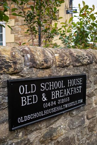 an old school house bed and breakfast sign on a stone wall at The Old School House in Haltwhistle