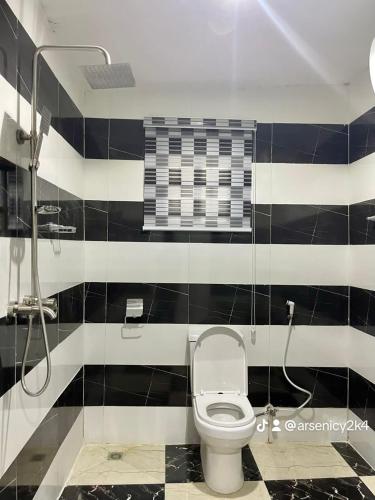 a bathroom with a toilet and black and white tiles at Allover suites & exclusive apartment in Abuja