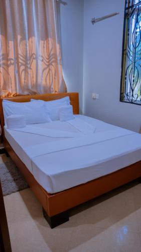 a bed with white sheets and pillows in a room at Hotel Rolax - Dodoma in Nkunjila
