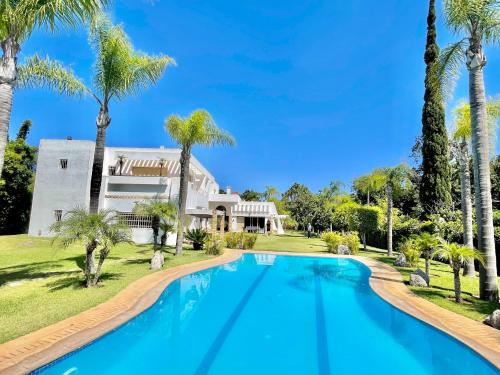 a swimming pool in front of a house with palm trees at villa dar esalam in Rabat
