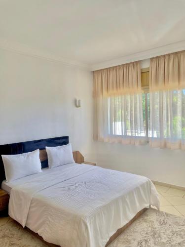 a white bedroom with a large bed and a window at villa dar esalam in Rabat