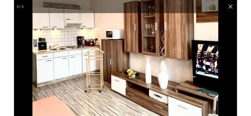 a small kitchen with white cabinets and a tv at FeWo Usedom Karlshagen in Karlshagen