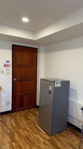 a room with a refrigerator and a wooden door at Rewadee House in Nonthaburi