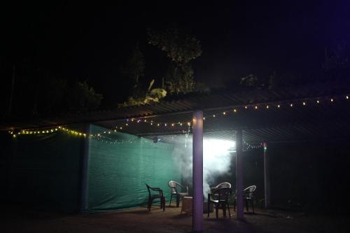 a table and chairs under a tent at night at Janhavi Homestay in Napoklu
