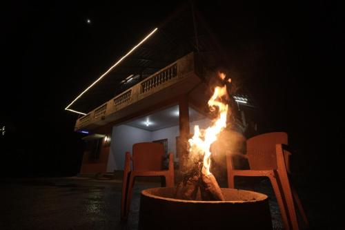 a fire pit in front of a building at night at Janhavi Homestay in Napoklu