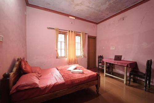 a bedroom with a bed and a desk with a laptop at Janhavi Homestay in Napoklu