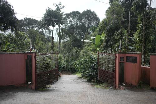 an entrance to a gate in a field with trees at Janhavi Homestay in Napoklu