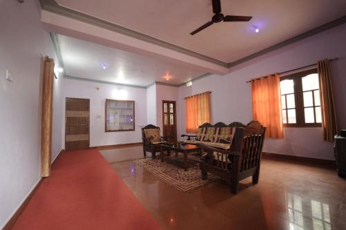 a living room with a ceiling fan and chairs at Janhavi Homestay in Napoklu