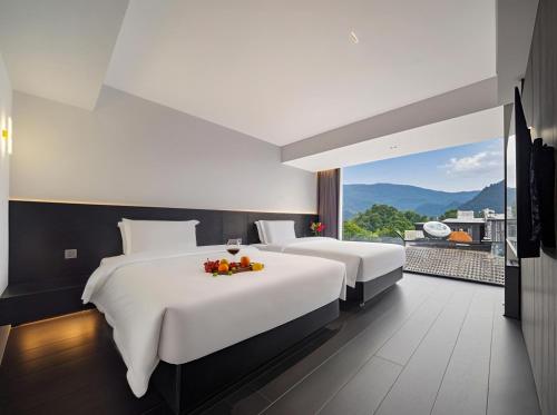 two beds in a hotel room with a view at 1982 Holiday Homestay in Zhangjiajie