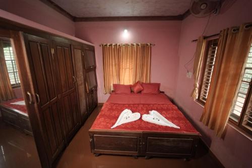 a bedroom with a bed with two white shoes on it at Janhavi Homestay in Napoklu