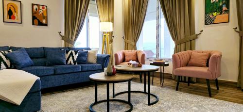 a living room with a blue couch and two pink chairs at Timbergrove Villa in Khānspur