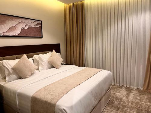 a hotel room with a large bed with white sheets at شقق همس البحر Hams Apartments in Ḑubā