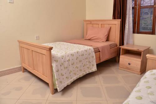 a small bedroom with a bed and a table at Aida's Gardens And Mable's Kitchen Entebbe in Entebbe