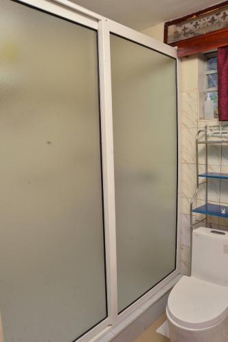 two sliding glass doors in a bathroom with a toilet at Aida's Gardens And Mable's Kitchen Entebbe in Entebbe