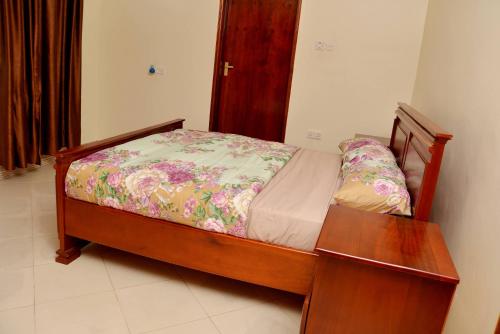 a bedroom with a bed and a wooden table at Aida's Gardens And Mable's Kitchen Entebbe in Entebbe