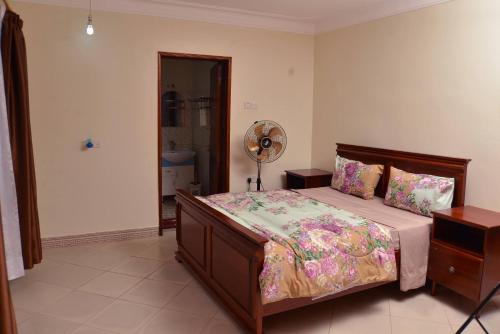 a bedroom with a bed and a fan at Aida's Gardens And Mable's Kitchen Entebbe in Entebbe