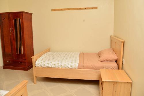 a small bedroom with a bed and a cabinet at Aida's Gardens And Mable's Kitchen Entebbe in Entebbe
