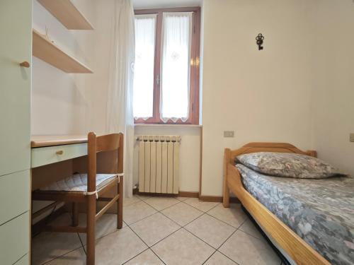 Un dormitorio con una cama y un escritorio y una ventana. en Terrazza Su Crosio a Clusone in centro!, en Clusone
