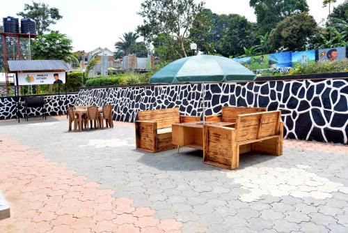 a table and chairs with an umbrella on a patio at Aida's Gardens And Mable's Kitchen Entebbe in Entebbe