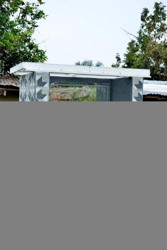 a building with a white roof with trees in the background at Aida's Gardens And Mable's Kitchen Entebbe in Entebbe