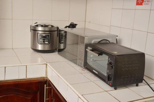 a toaster oven sitting on a counter next to a microwave at Aida's Gardens And Mable's Kitchen Entebbe in Entebbe