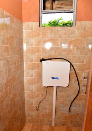 a bathroom with a toilet in a tiled wall at Aida's Gardens And Mable's Kitchen Entebbe in Entebbe
