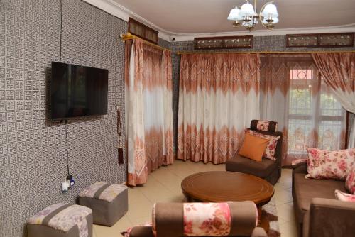 a living room with a couch and a table at Aida's Gardens And Mable's Kitchen Entebbe in Entebbe