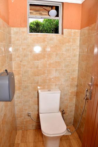 a bathroom with a toilet and a window at Aida's Gardens And Mable's Kitchen Entebbe in Entebbe