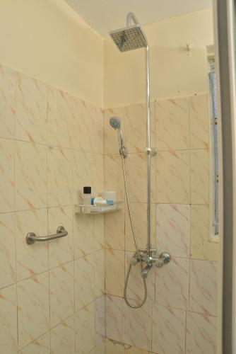 a shower with a shower head in a bathroom at Aida's Gardens And Mable's Kitchen Entebbe in Entebbe
