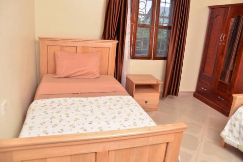a bedroom with a bed with a wooden headboard at Aida's Gardens And Mable's Kitchen Entebbe in Entebbe