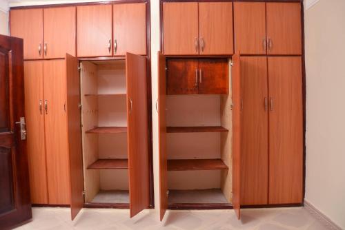 an empty closet with wooden cabinets in a room at Aida's Gardens And Mable's Kitchen Entebbe in Entebbe