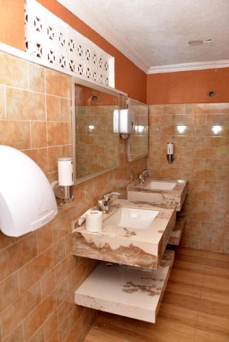 a bathroom with two sinks and a mirror at Aida's Gardens And Mable's Kitchen Entebbe in Entebbe