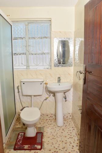 a bathroom with a toilet and a sink at Aida's Gardens And Mable's Kitchen Entebbe in Entebbe