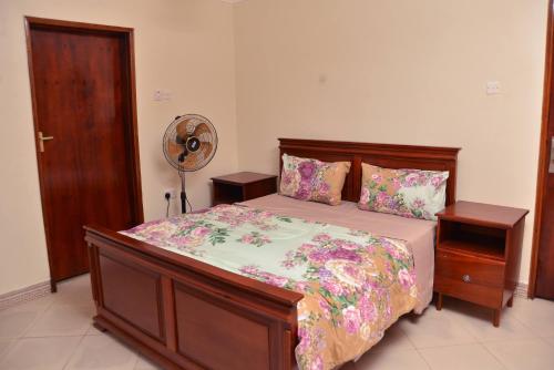 a bedroom with a bed and a fan at Aida's Gardens And Mable's Kitchen Entebbe in Entebbe