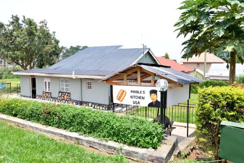 a small white house with a sign on it at Aida's Gardens And Mable's Kitchen Entebbe in Entebbe