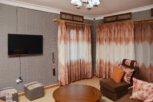 a living room with a couch and a table at Aida's Gardens And Mable's Kitchen Entebbe in Entebbe