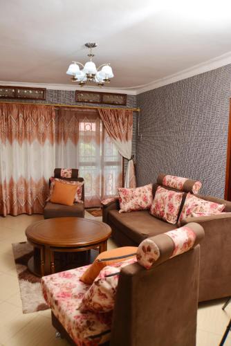 a living room with two couches and a table at Aida's Gardens And Mable's Kitchen Entebbe in Entebbe