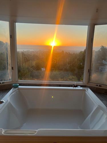 a bath tub in front of a window with the sunset at Big Bright Burlingame Hills Bay View Home in Burlingame