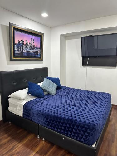Schlafzimmer mit einem Bett mit blauer Bettwäsche und einem Flachbild-TV in der Unterkunft Corferias, Apt302 BIG, American Embassy, Agora,Embajada in Estación El Salto