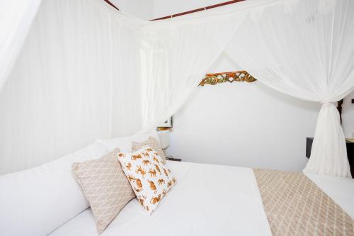 a white bedroom with white curtains and a bed with a pillow at Bali Style Boutique Hotel in Las Terrenas