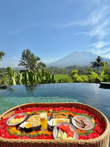 a tray of food on a table next to a body of water at Avina Stays - Neve's Bamboo houses in Selat