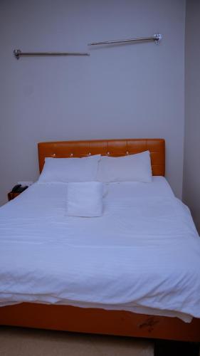 a bed with white sheets and pillows on it at Hotel Rolax - Dodoma in Nkunjila