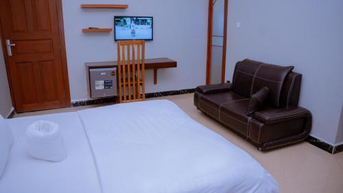 a bedroom with a bed and a chair and a tv at Hotel Rolax - Dodoma in Nkunjila