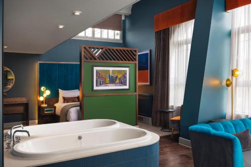 a bathroom with a tub in a room with a bed at Malmaison Newcastle in Newcastle upon Tyne