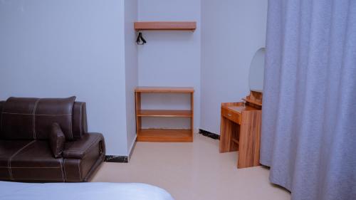a room with a couch and a chair and a television at Hotel Rolax - Dodoma in Nkunjila