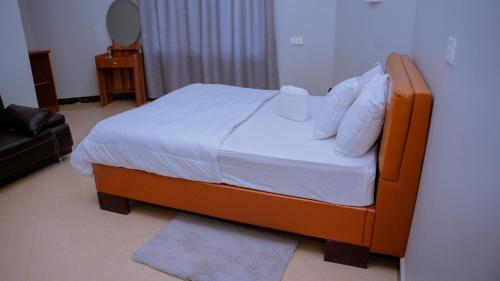 a bedroom with a bed with white sheets and pillows at Hotel Rolax - Dodoma in Nkunjila
