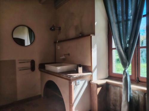 a bathroom with a sink and a mirror and a window at La Glane at Le Maingaud in Saulgond
