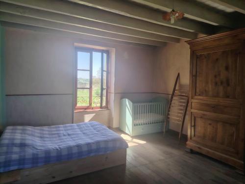 a bedroom with a bed and a window and a crib at La Glane at Le Maingaud in Saulgond
