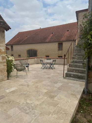 a patio with a table and chairs in front of a building at Détente et charme au Domaine in Coust